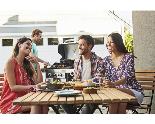 Gruppe von Freunden grillt und isst gemeinsam im Freien.