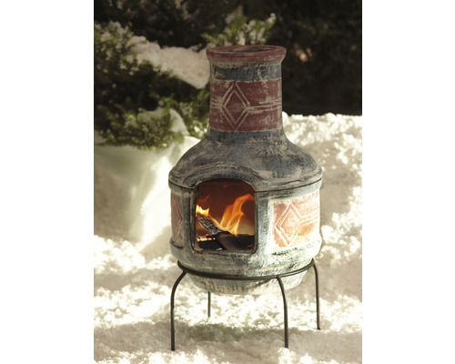 Mexikanischer Ofen mit Dekoration und Feuer auf einem Metallständer im Schnee.
