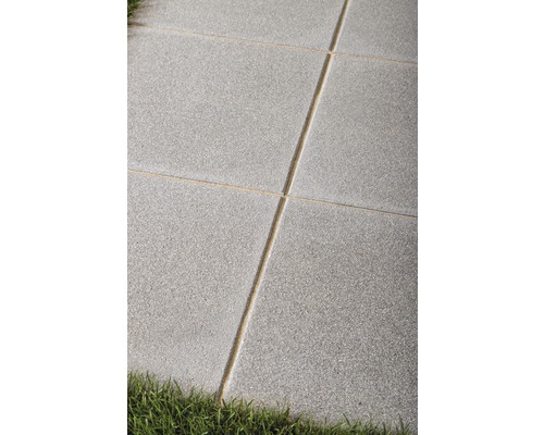 Nahaufnahme von grauen Terrassenplatten mit Gras