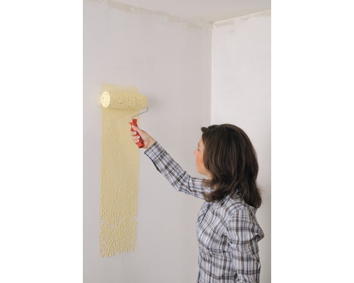 Frau streicht Wand mit Farbroller