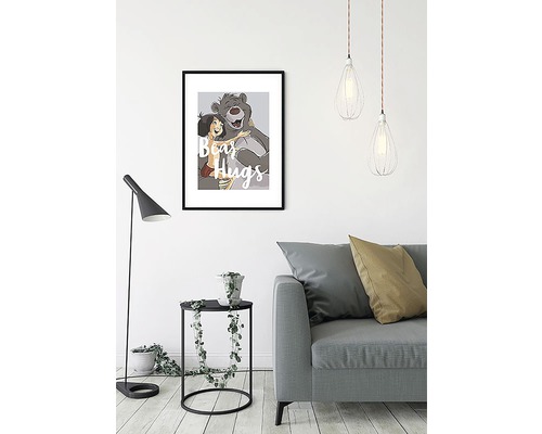 Dekoratives Bild mit dem Bären Balu und Mogli mit dem Text Bärenumarmung in einem Wohnzimmer.