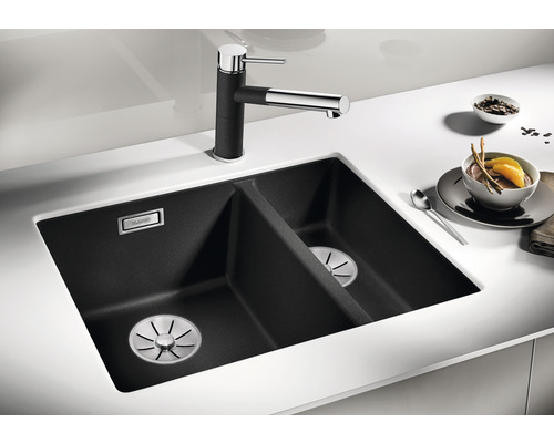 Schwarzes Spülbecken mit zwei Becken und Armatur auf einer hellen Arbeitsplatte.