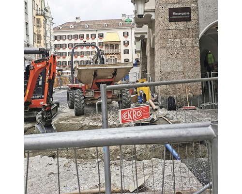 Baustelle mit Minibagger und Transportfahrzeug in der Stadt.