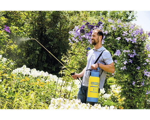 Mann verwendet Gartenspritze Gloria im Garten zwischen Pflanzen