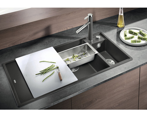 Küchenspüle mit Abtropffläche, Schneidebrett, Sieb und Armatur.