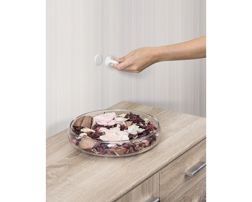 Dekoschale mit Potpourri auf Kommode und Hand beim Öffnen eines Schranks