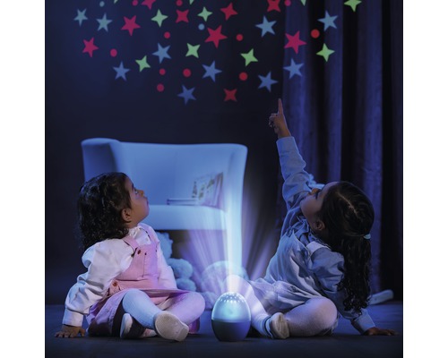 Zwei Kinder sitzen im Dunkeln und schauen auf eine Projektion von Sternen an der Wand, die von einem Projektor erzeugt wird.