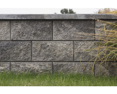 Mauer aus Betonsteinen mit Gras im Garten