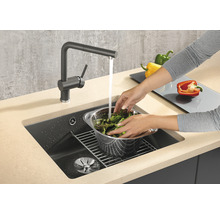 Person wäscht Salat in einem Spülbecken mit Wasserhahn.