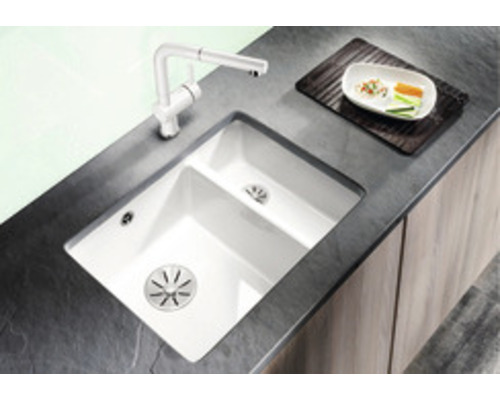 Küchenspüle mit Abtropffläche, Armatur und Geschirr auf einer Arbeitsplatte.