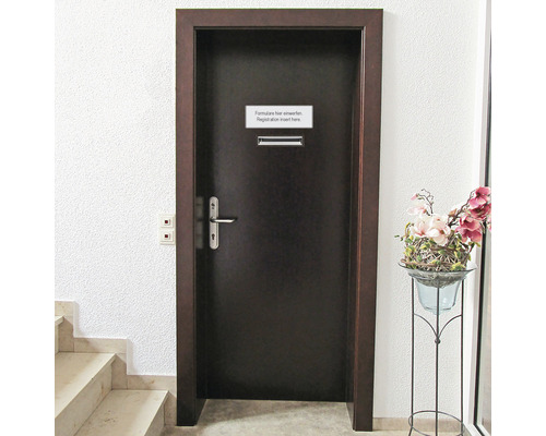 Tür mit Briefkasten und Hinweisschild