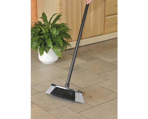 Eine Kehrbesen mit Stiel wird auf einem gefliesten Boden verwendet.