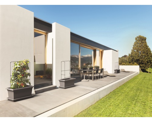 Terrasse mit modernem Haus, Esstischgruppe und bepflanzten Pflanzkästen mit Rankgitter