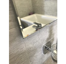 Detailaufnahme eines Spiegels im Badezimmer, der eine Badewanne und eine Armatur reflektiert.