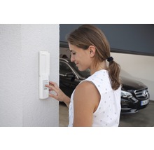 Frau bedient ein Garagentor mit Zahlencode