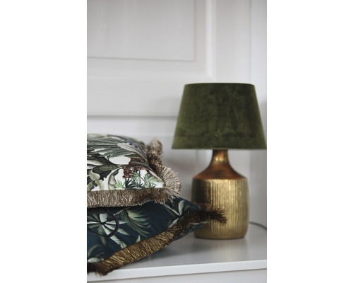 Dekorative Kissen mit Fransen und eine Tischleuchte auf einem Regal.