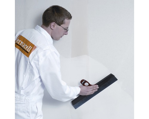 Handwerker glättet Wand mit Flächenspachtel
