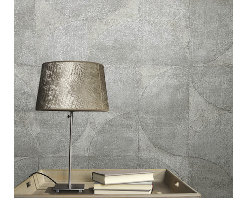 Nahaufnahme einer strukturierten Tapete mit Kreismuster, ergänzt durch eine Tischleuchte und Bücher auf einem Tablett