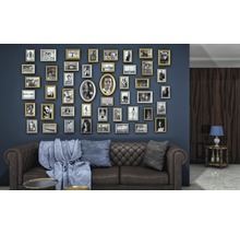 Wohnzimmer mit braunem Ledersofa, blauen Kissen und einer Wand voller Bilderrahmen