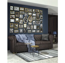 Wohnzimmer mit braunem Ledersofa, Couchtisch und einer Wand voller Bilderrahmen.