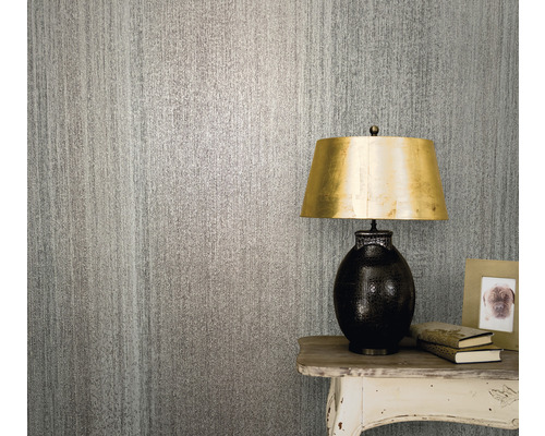 Nahaufnahme einer strukturierten Tapete mit einer Tischlampe, Büchern und einem Bilderrahmen auf einem Beistelltisch.