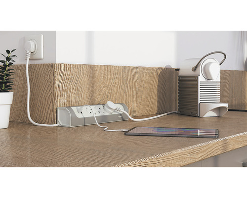 Mehrfachsteckdose mit angeschlossenem Mobiltelefon und Kaffeemaschine auf einer Arbeitsplatte