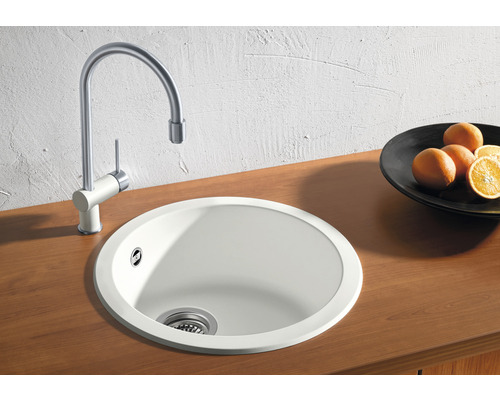Rundes Spülbecken mit Wasserhahn auf einer Holzoberfläche.