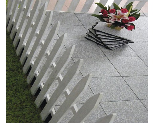 Szene mit grauen Terrassenfliesen, weißem Zaun und Blumenstrauß