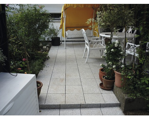 Terrasse mit Gartenmöbeln und Pflanzen auf Steinfliesen