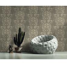 Raumansicht mit gemusterter Tapete, Sessel, Kaktus und Dekoration