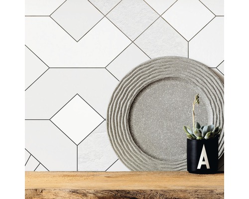 Dekorative Wandfliesen mit geometrischem Muster, Zierteller und Topfpflanze auf Holzregal.