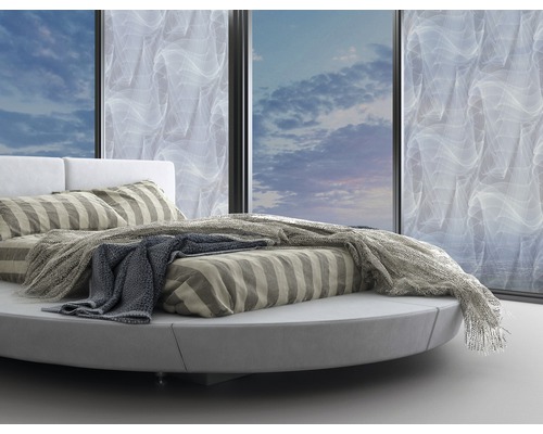 Rundes Bett mit gestreifter Bettwäsche und Tagesdecke vor Fenster