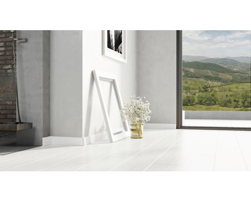 Heller Raum mit weißem Holzboden, zwei Bilderrahmen und einem Blumenstrauß.