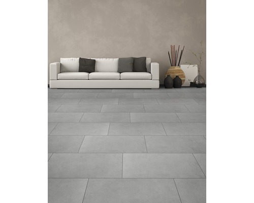 Heller Wohnraum mit Bodenfliesen, Sofa und Dekorationsgegenständen.