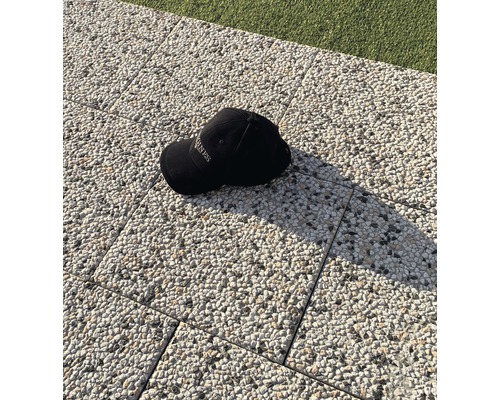 Eine schwarze Kappe liegt auf Pflastersteinen.