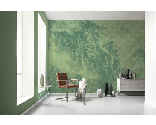 Wohnraum mit grüner Tapete mit Bergmotiv, Sessel und Kommode