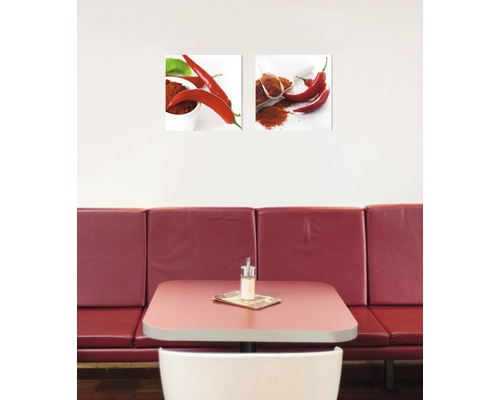 Zwei Wandbilder mit Chili-Motiven über einem Tisch