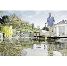 Mann bedient eine gelbe Tauchpumpe im Teich