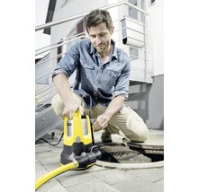 Mann hockt neben einem Gullydeckel und bedient eine gelbe Schmutzwasserpumpe.