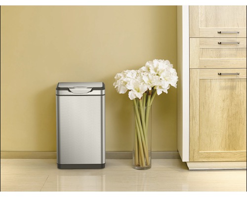 Szene mit einem rechteckigen Mülleimer aus Edelstahl, einem Blumenstrauß in einer Vase und einem Küchenschrank.