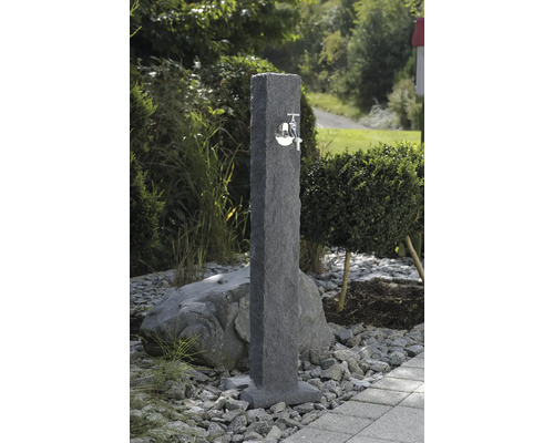 Gartenszene mit einer Wasserzapfsäule aus Stein mit einem Wasserhahn aus Metall.