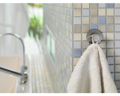 Ein Handtuch hängt an einem runden, silberfarbenen Haken vor einer gefliesten Wand im Badezimmer.