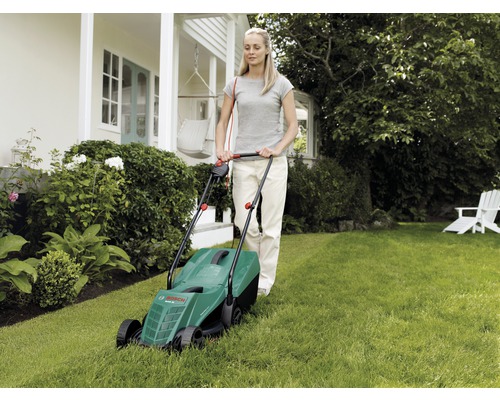 Frau bedient einen Rasenmäher im Garten.