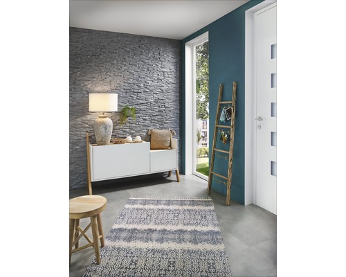 Wohnraum mit Steinwand, Kommode, Lampe, Teppich und Holzleiter