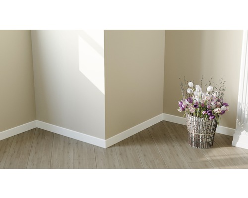 Helle Ecke eines Raumes mit Laminatboden, Sockelleisten und einem Blumenarrangement in einem silberfarbenen Korb