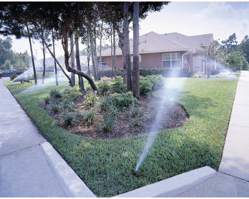 Bewässerungssystem für einen Rasen und eine Gartenfläche vor einem Wohnhaus.