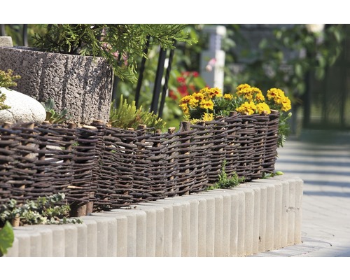 Dekorative Beetumrandung aus Weide und Betonsteinen im Garten.