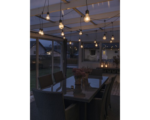 Terrasse mit Tisch, Stühlen und Lichterkette für eine stimmungsvolle Atmosphäre.