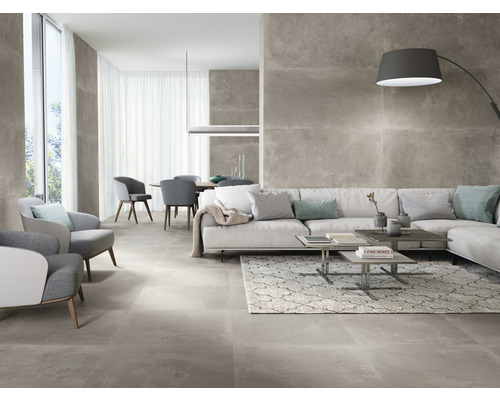 Helles Wohnzimmer mit grauen Bodenfliesen, Sofa, Sesseln und Esstisch