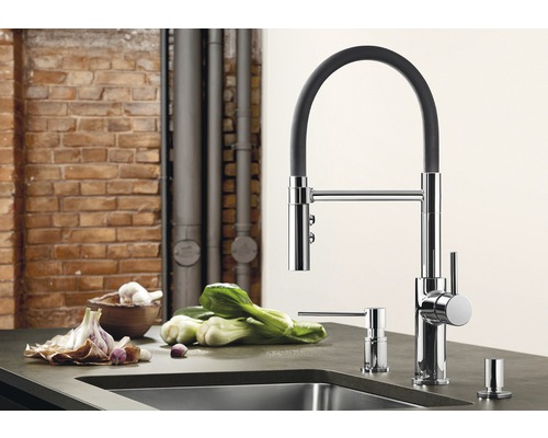 Küchenszene mit Spültischarmatur, Seifenspender und Gemüse auf einer Küchentheke.